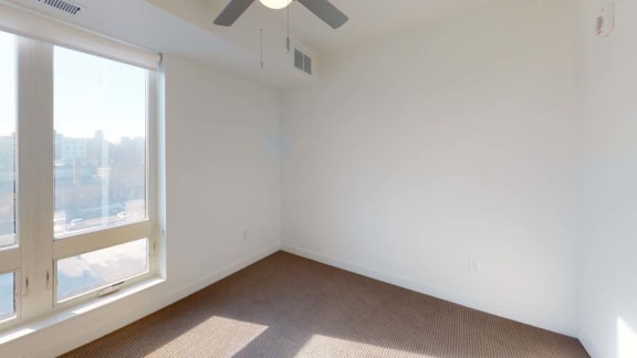 an empty room with a large window and a ceiling fan