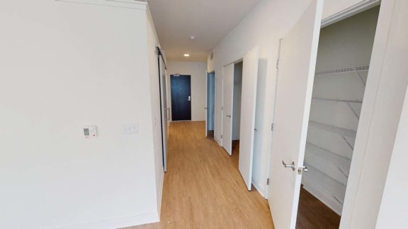 a hallway with white walls and a closet