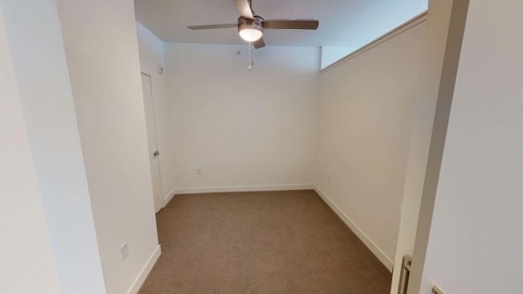 an empty room with a ceiling fan and a carpet