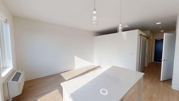 an empty living room with a white table and a kitchen