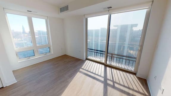 an empty living room with large windows and wooden floors