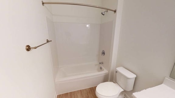 a white bathroom with a white toilet and a bath tub