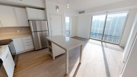 an empty kitchen with a stainless steel refrigerator and a table