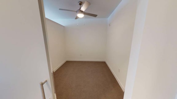 an empty room with a ceiling fan and a carpet