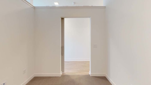 an empty room with a white wall and an open door