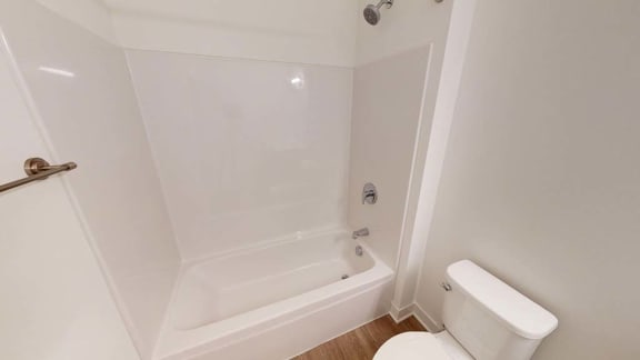a white bathroom with a white toilet and a bath tub