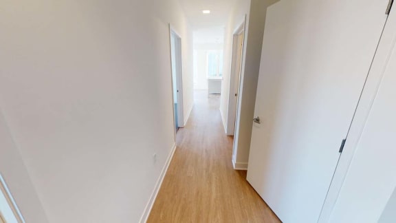 a hallway with white walls and a wooden floor
