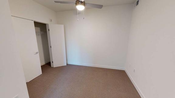an empty room with a ceiling fan and a closet
