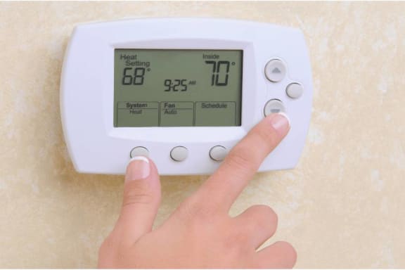 a person is pointing at a timer on a thermostat