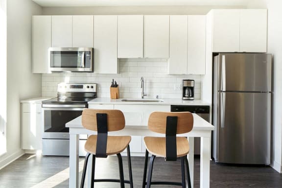 a kitchen with white cabinets and a table with three chairs