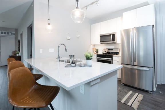 a kitchen with a large island and a stainless steel refrigerator
