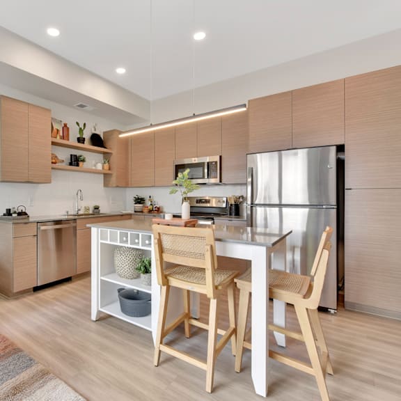 A modern kitchen with wooden chairs and a white island.