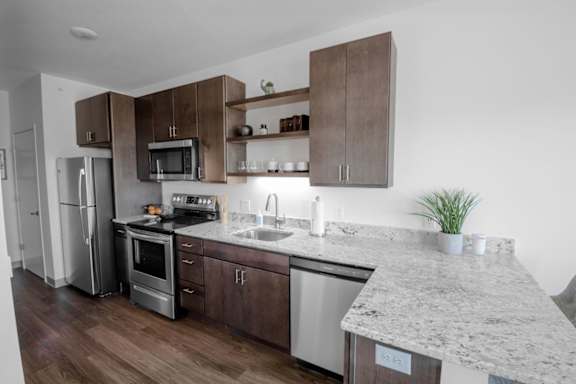 A kitchen with a granite countertop and stainless steel appliances.