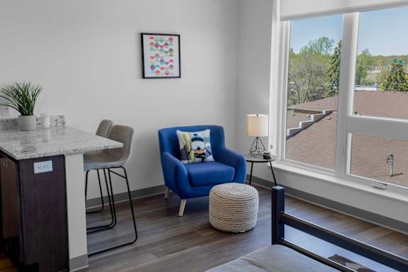 A blue chair with a cartoon character on it is in the middle of a room with a table and a plant.
