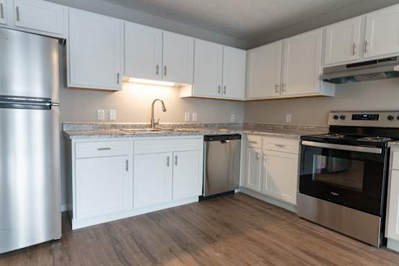 Floor Plan  A kitchen with white cabinets and a stainless steel refrigerator.