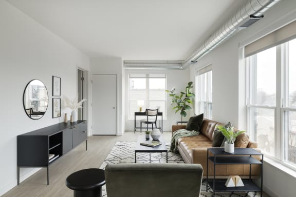 a living room with a brown couch and a black and white rug