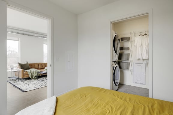 a bedroom with a yellow bed and a closet with clothes in it