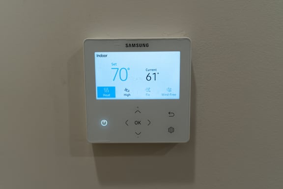 A Samsung thermostat shows the indoor temperature as 70 degrees and the current temperature as 61 degrees.