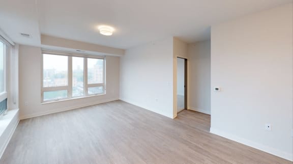 an empty living room with a large window and wood flooring