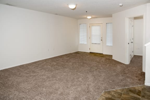 an empty living room with carpet and white walls and doors