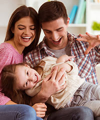 A family of three is sitting on a couch.