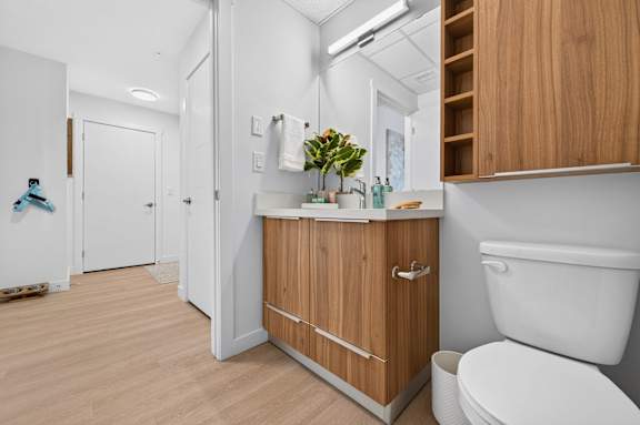 A white toilet sits next to a wooden cabinet in a bathroom.