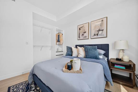 A bedroom with a bed, nightstand, and two pictures on the wall.