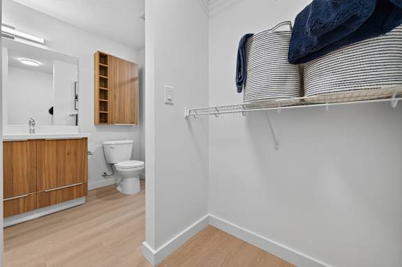 A white bathroom with a toilet and a shelf.
