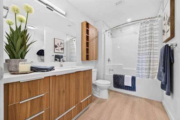 A bathroom with a white counter top and wooden drawers.