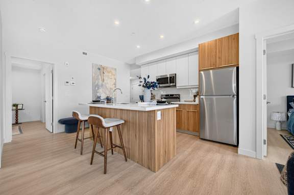 A modern kitchen with wooden cabinets and a stainless steel refrigerator.