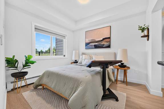 A bedroom with a large bed and a painting on the wall.