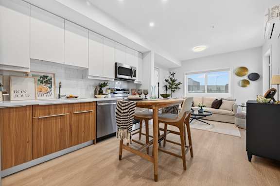 A modern kitchen with wooden chairs and a dining table.