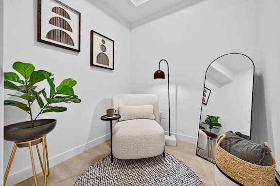 A living room with a chair, a plant, and a lamp.
