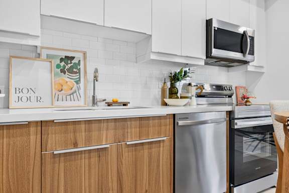 A kitchen with wooden cabinets and a white backsplash.