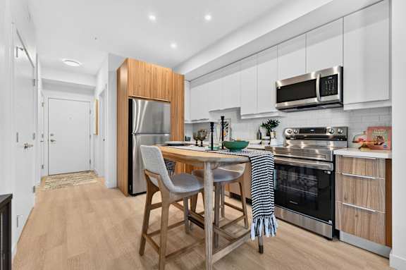 A modern kitchen with a wooden island and stainless steel appliances.