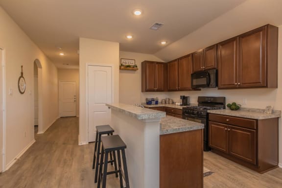 a kitchen with dark wood cabinets and an island with granite countertops at The Village at Granger Pines, Conroe, 77302