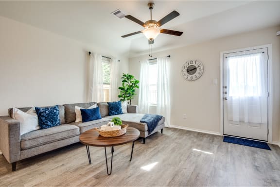a living room with a couch coffee table and ceiling fan