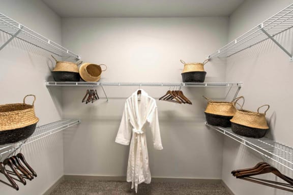 a walk in closet with a white robe and wicker baskets at The Pointe at Valley Ranch Town Center, New Caney, Texas