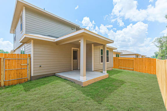 a home with a wooden fence and a green lawn at The Village at Granger Pines, Conroe, TX
