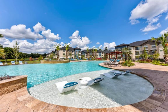 a large pool with lounge chairs and lounge chairs in front of a building at The Pointe at Valley Ranch Town Center, Texas