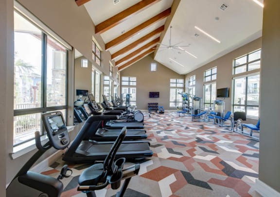 a large fitness room with cardio equipment and large windows at The Pointe at Valley Ranch Town Center, Texas, 77357