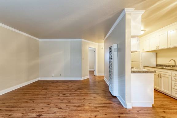 A kitchen with white cabinets and a wooden floor.