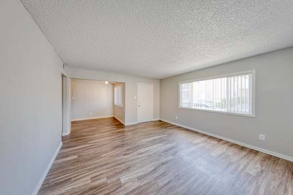 A room with wooden flooring and a window with blinds.