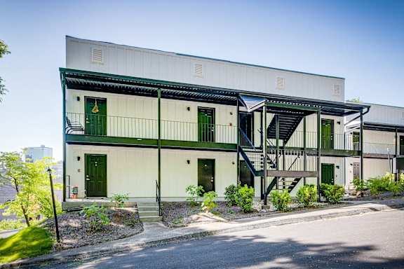 A white building with green doors and a staircase.