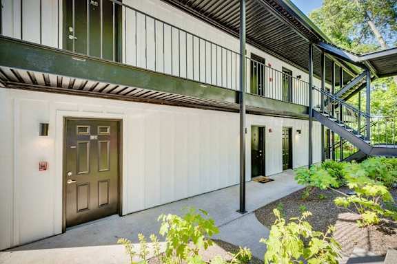 A modern building with a metal staircase and a green door.