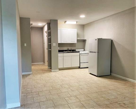 A kitchen with white cabinets and a refrigerator.