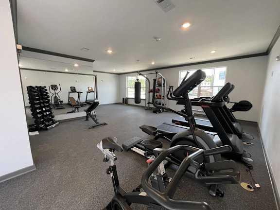 A spacious gym with a variety of equipment including treadmills, stationary bikes, and weight machines.
