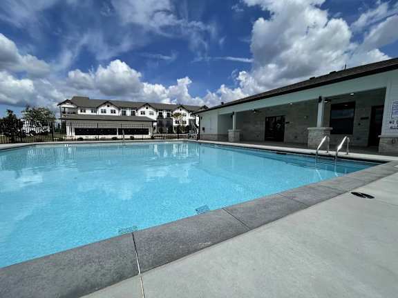 A large swimming pool with a building in the background.