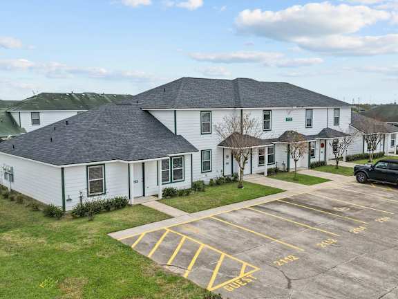 A white building with a parking lot in front of it.
