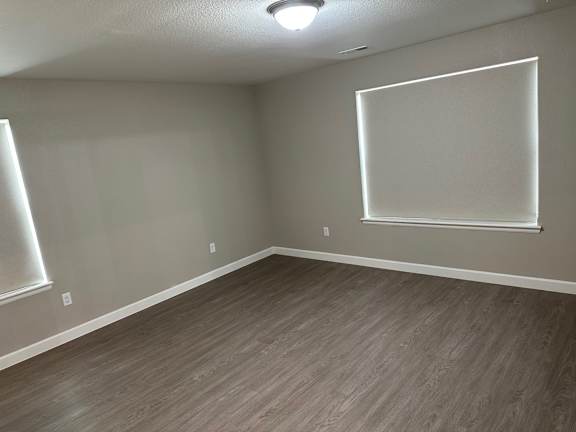 an empty living room with wood floors and gray walls